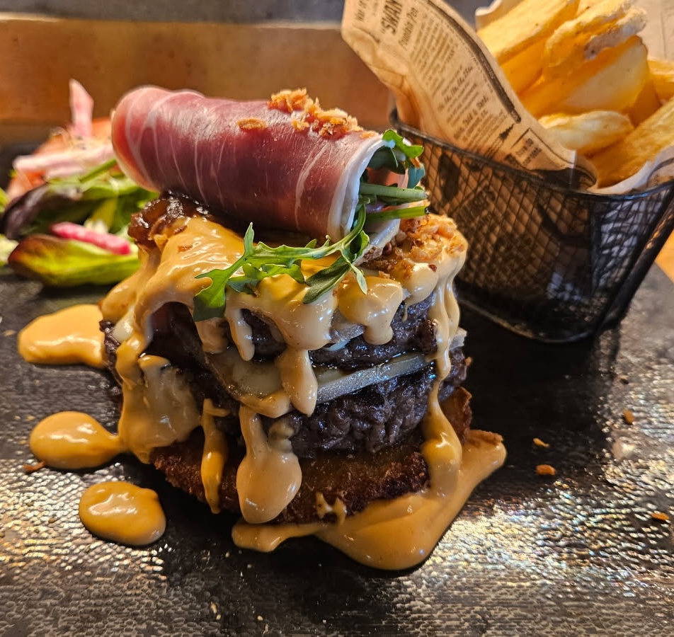 BURGER double steak haché, galette de pommes de terre, steak haché façon bouchère 150g, compotée d’oignons, jambon sec, fromage*, roquette, sauce burger, frites